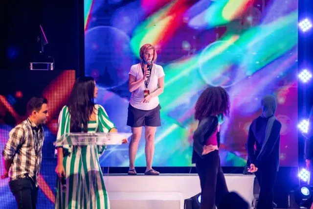 Susan speaking on stage in front of a colourful video wall