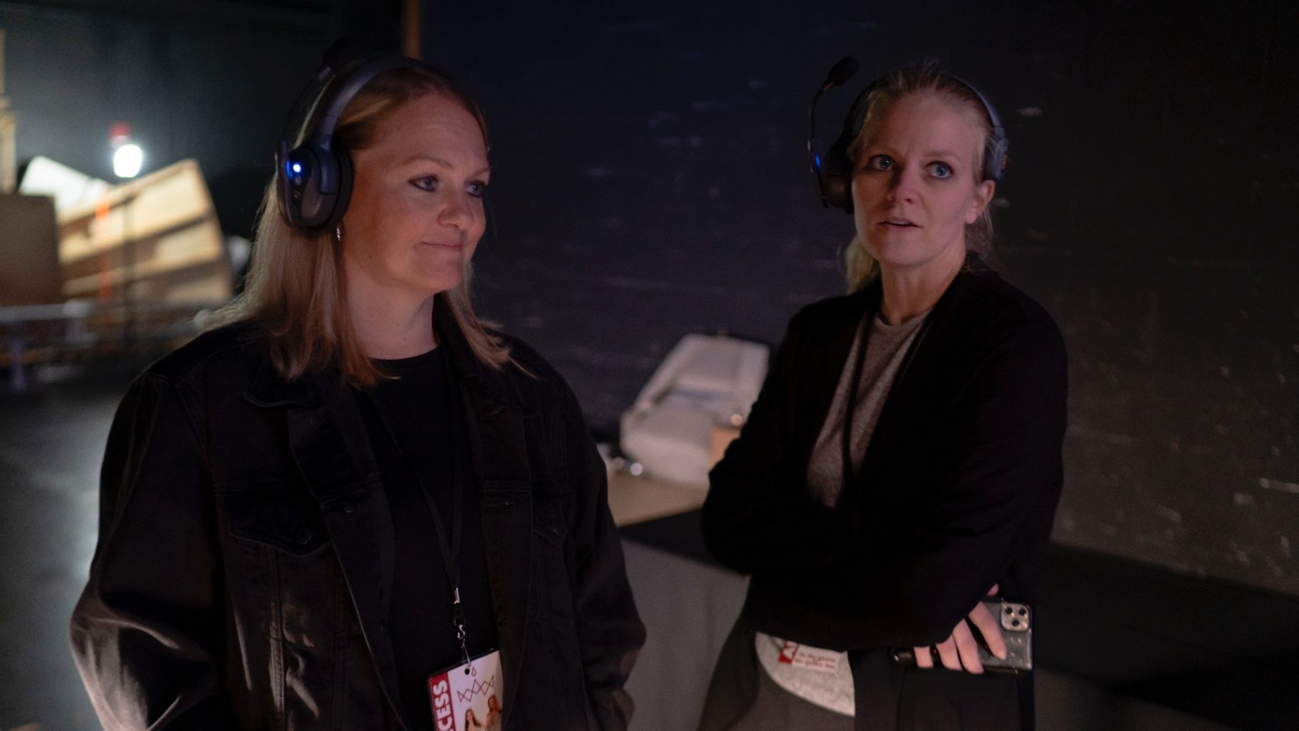 Two crew members wearing headsets backstage
