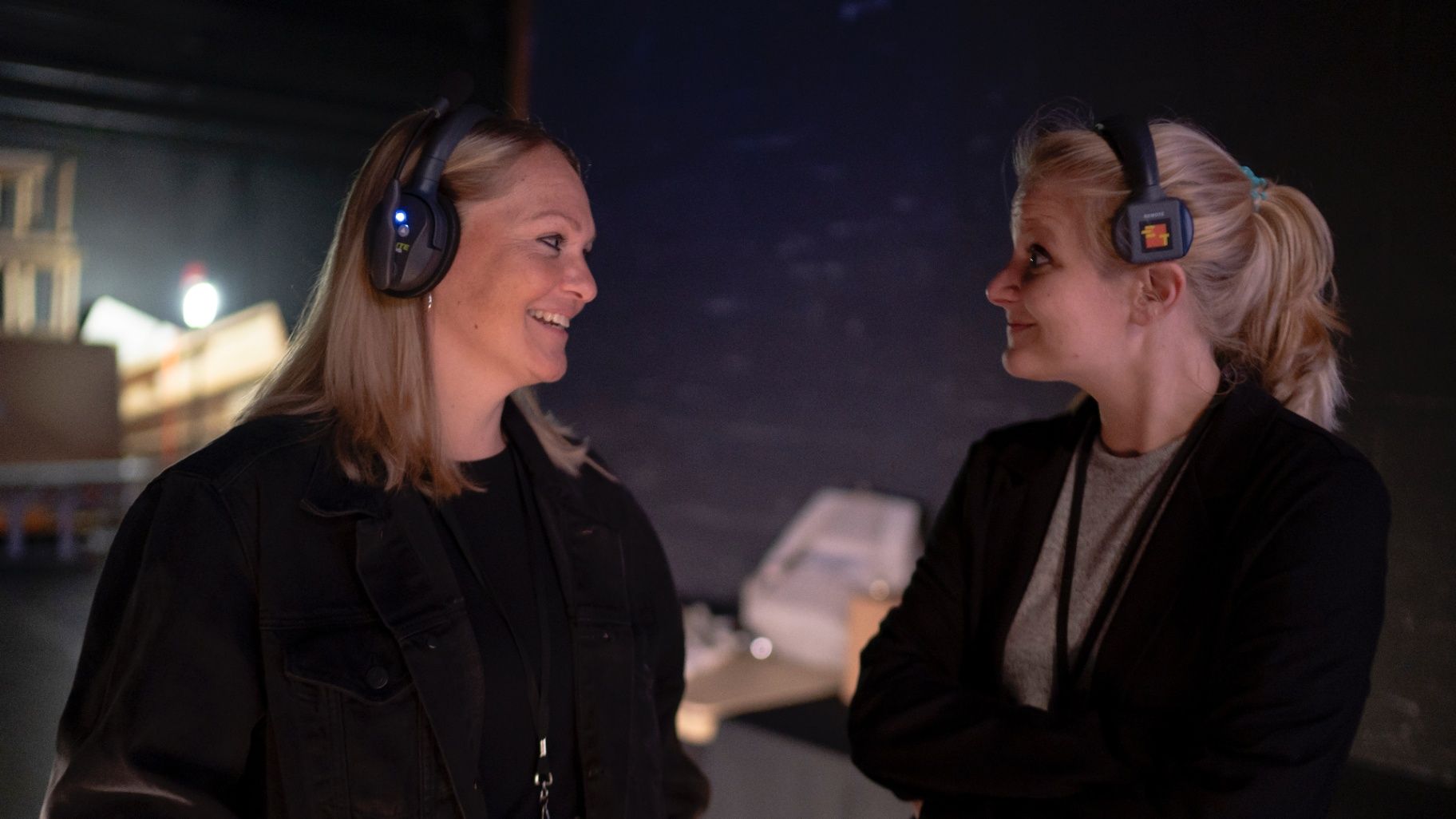 Two crew members smiling at each other backstage